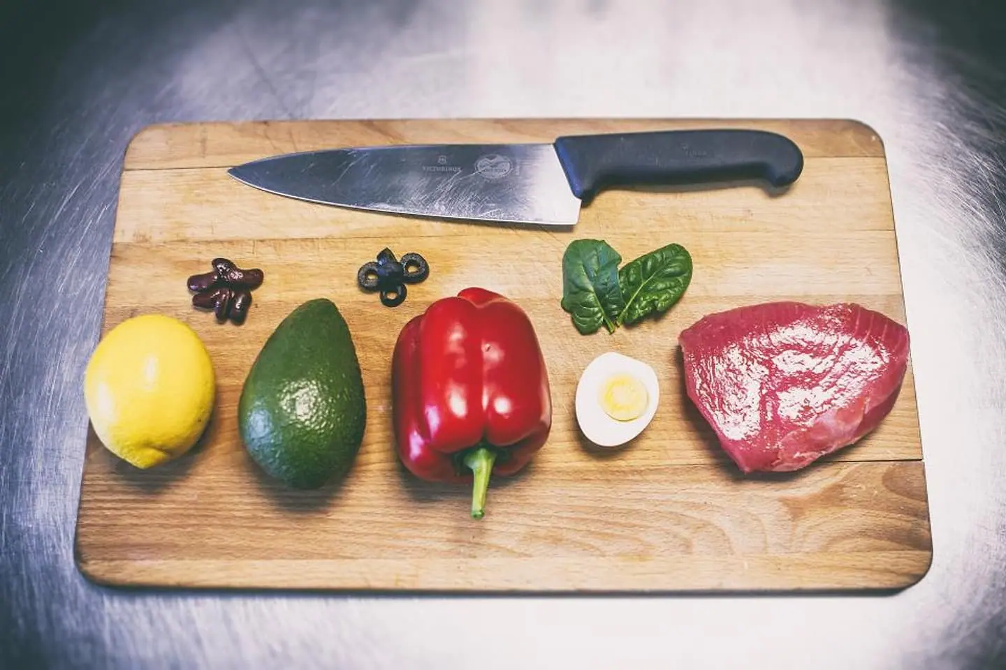 Schneidebrett mit Messer, Avocado, Paprika, Ei und Fleisch