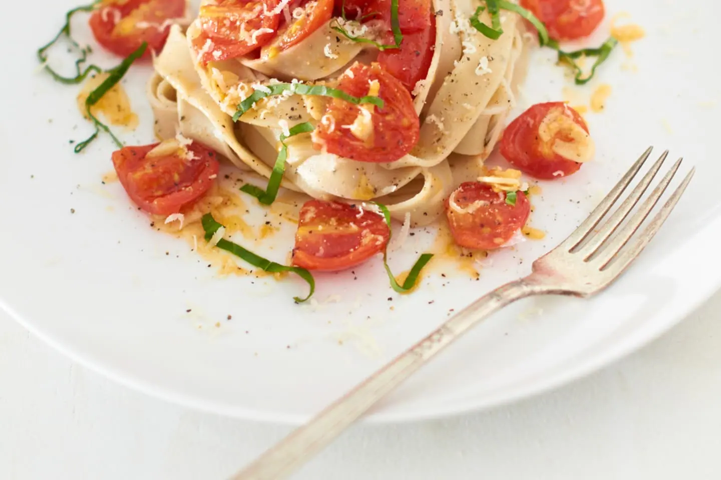 Cremige Pasta mit Hähnchen, Kirschtomaten und frischen Kräutern auf einem weißen Teller