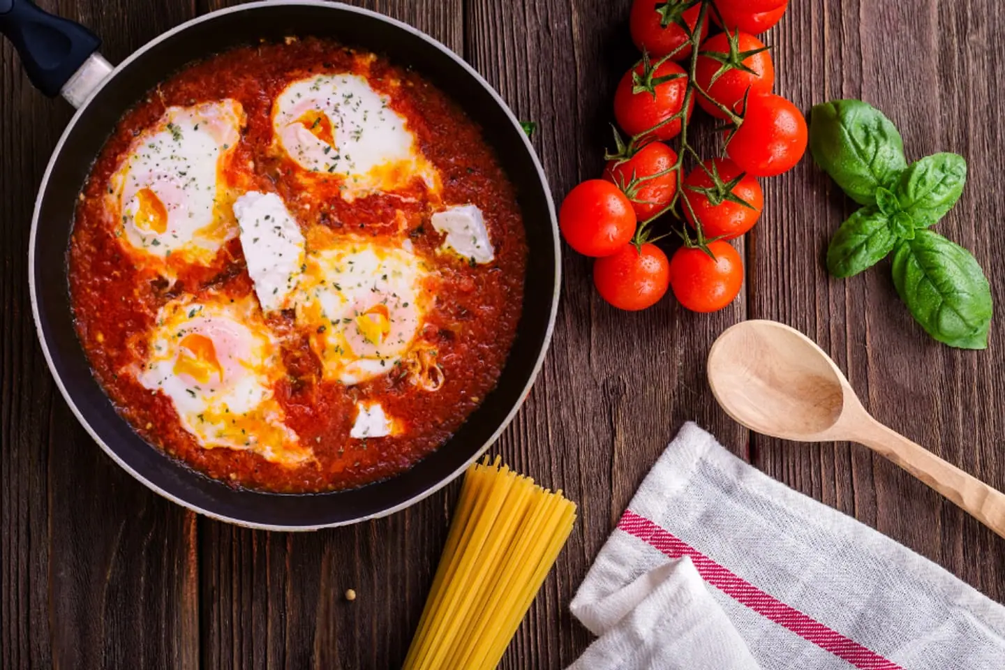 Pfanne mit Tomatensauce, pochierten Eiern und Feta