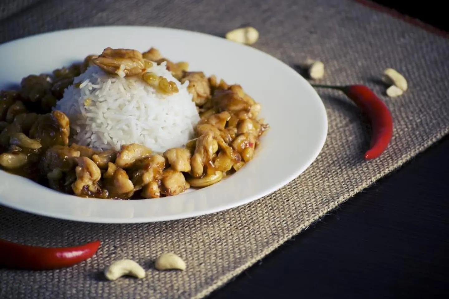 Hähnchen in glänzender Sauce mit Reis und Cashewkernen auf einem Teller